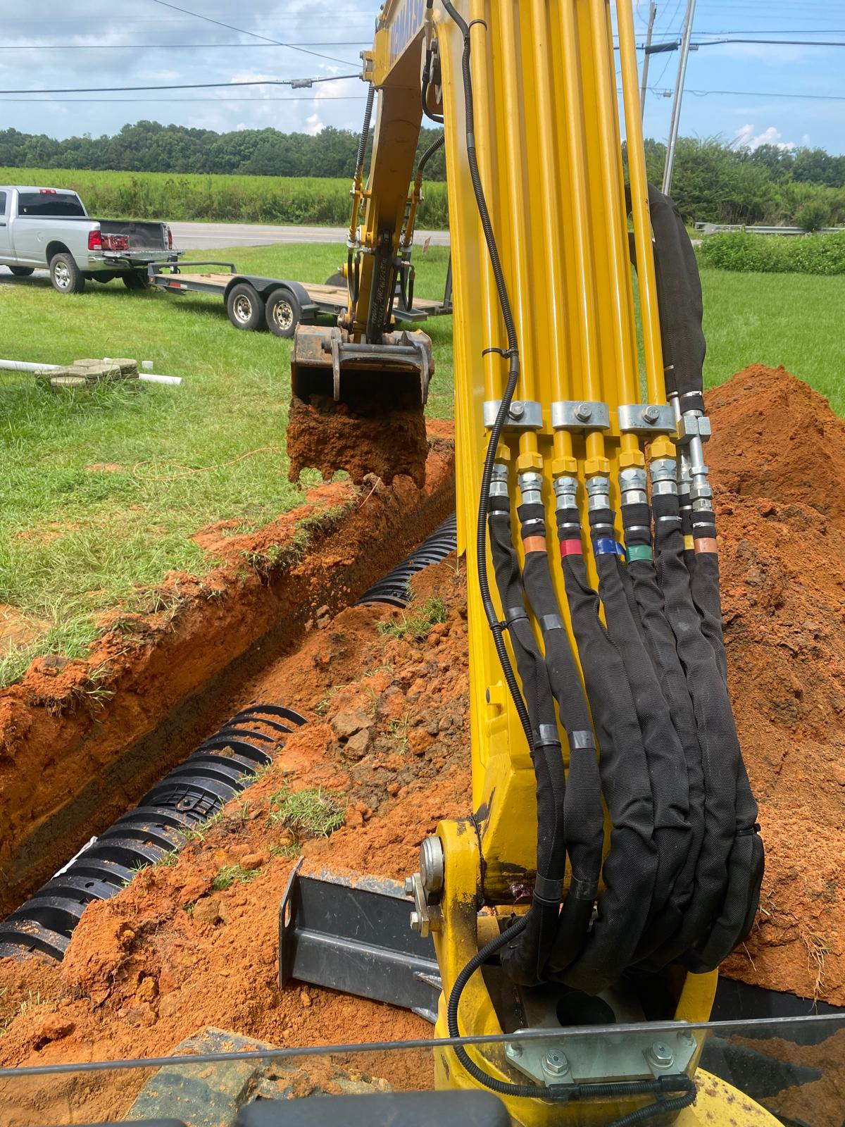 Dirt pile next to an open trench with utility pipes.