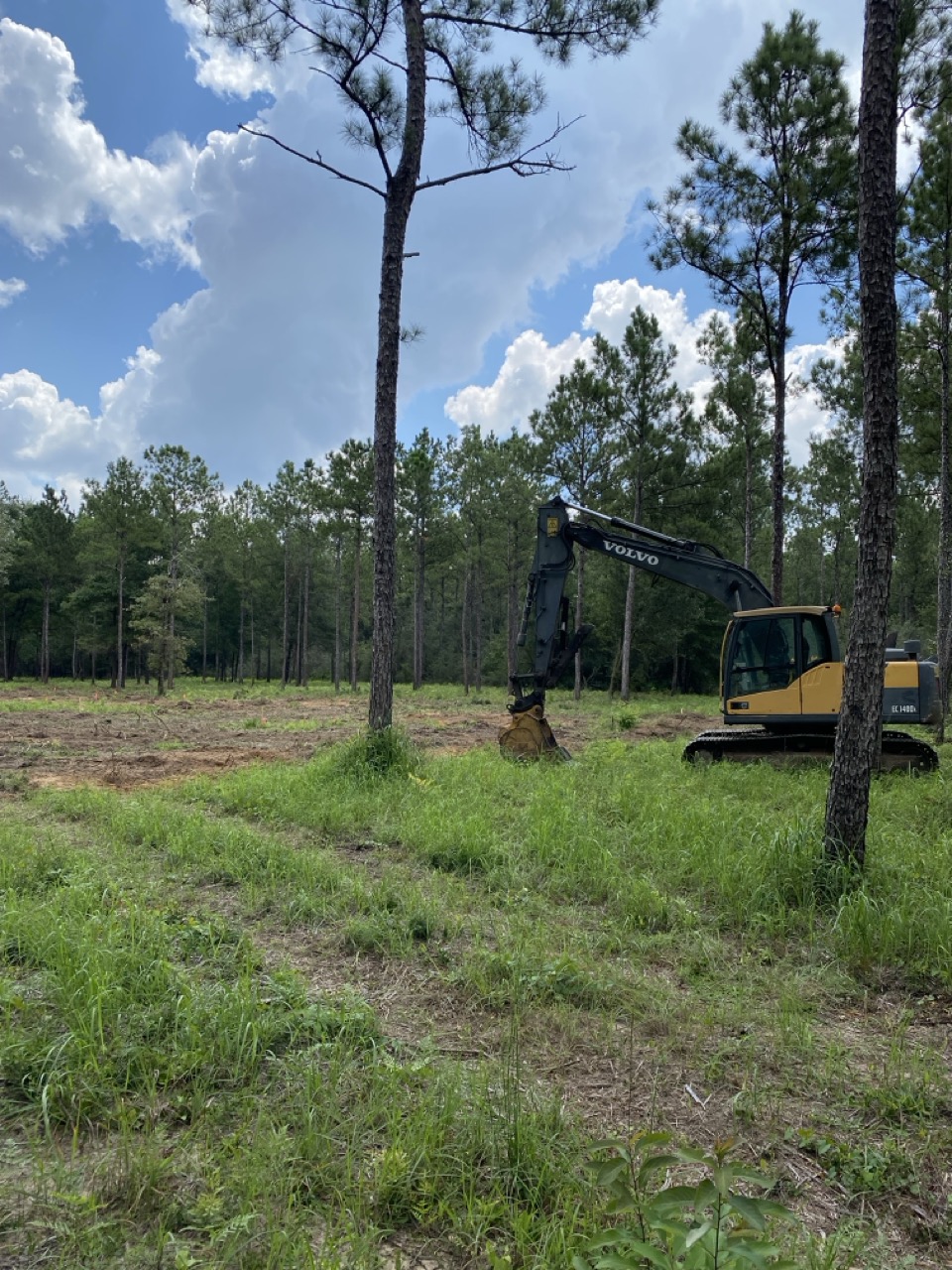 White house by a stream with a view of a forested hill.