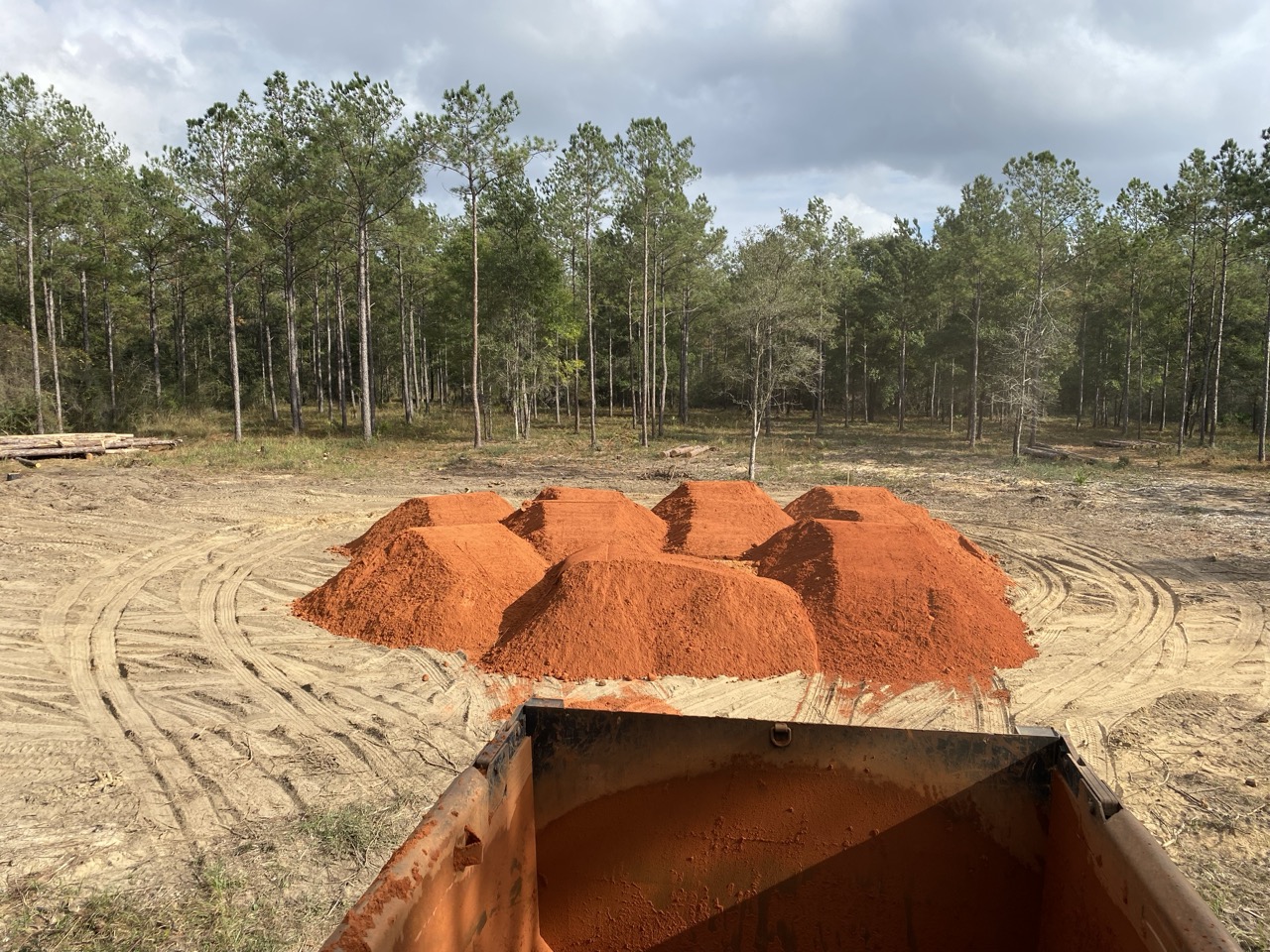 Dirt pile next to an open trench with utility pipes.