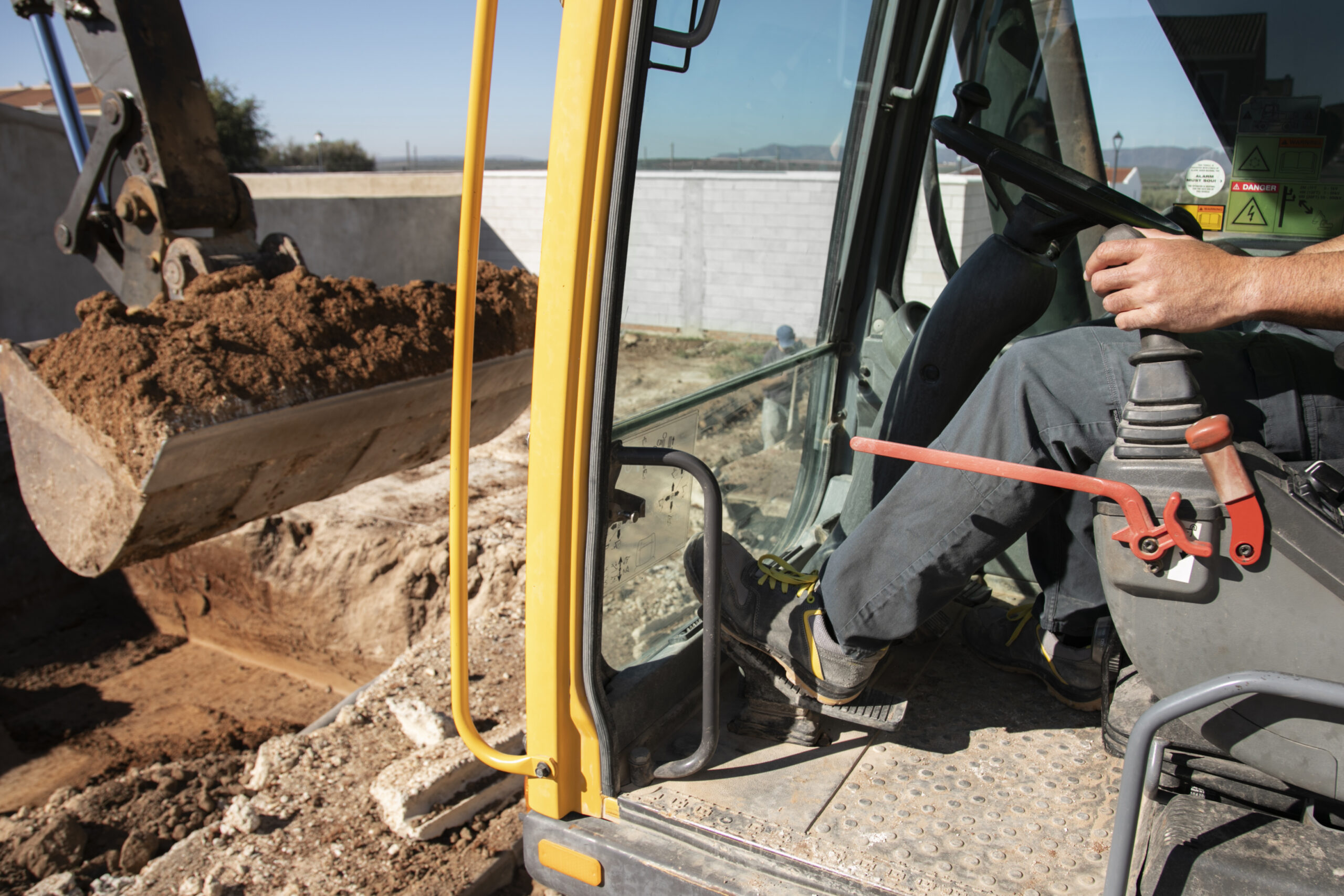 Dirt pile next to an open trench with utility pipes.