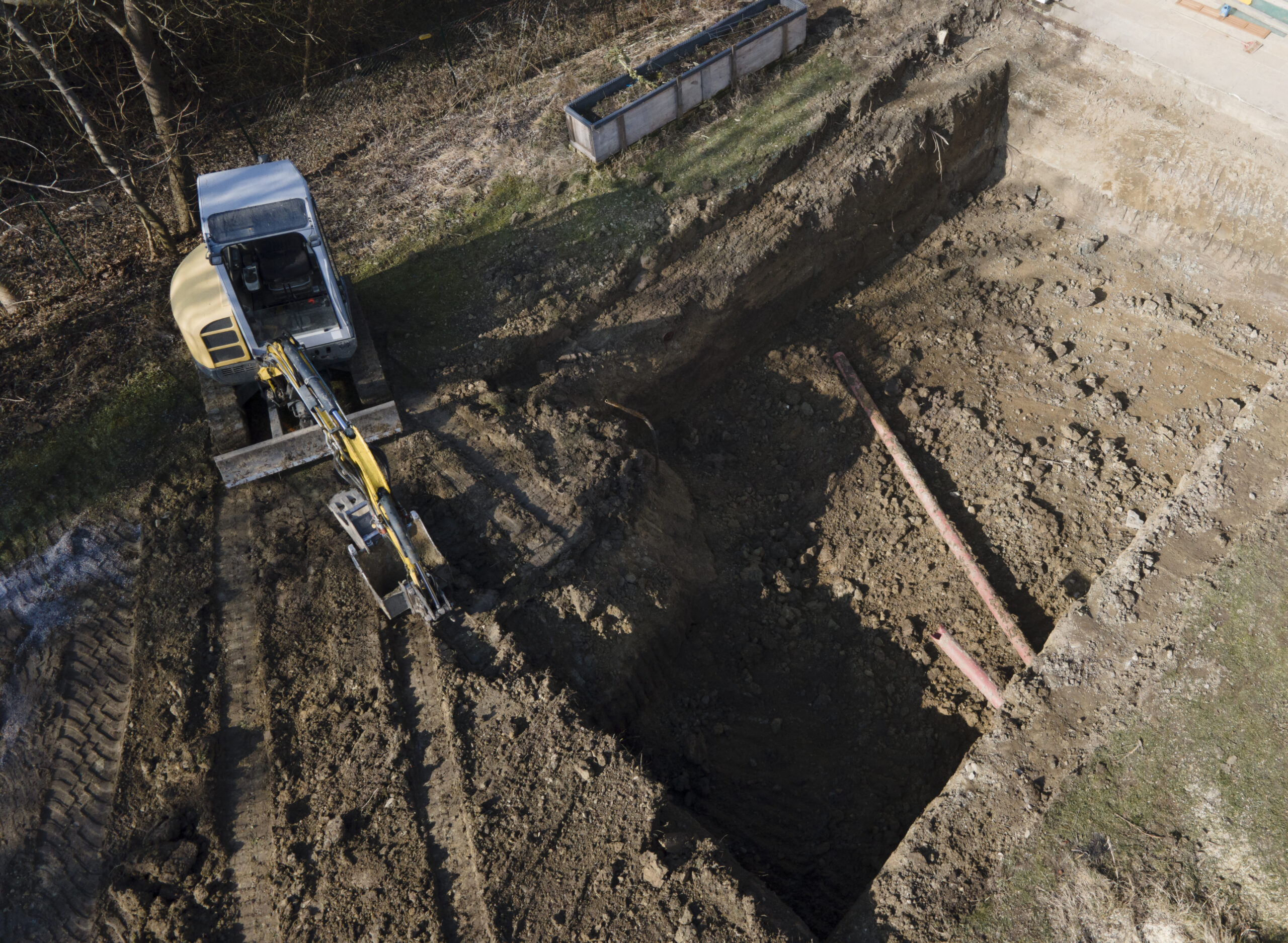 Dirt pile next to an open trench with utility pipes.